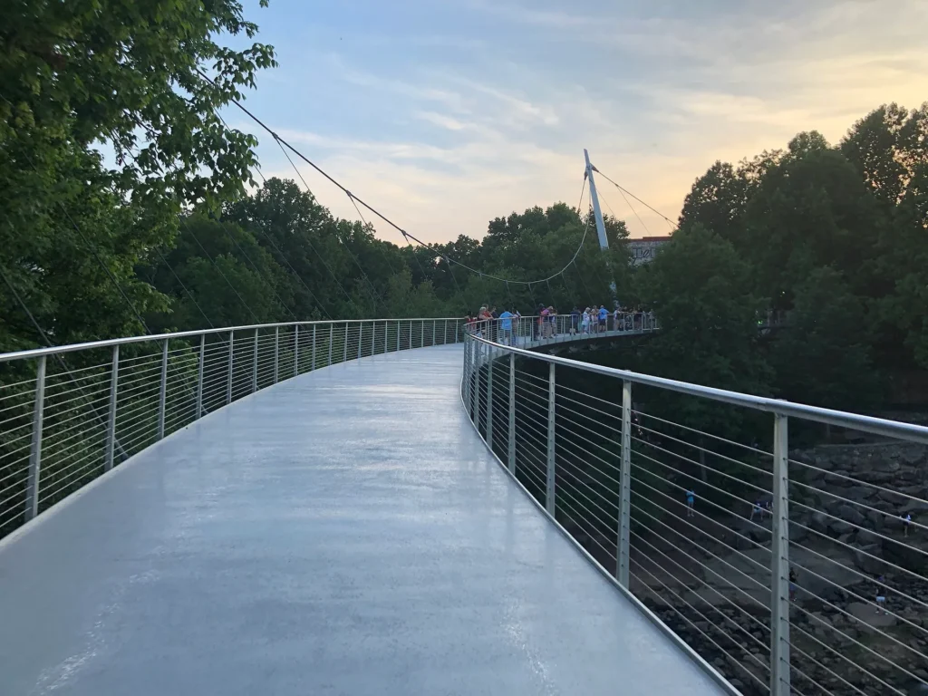 Puente peatonal Liberty Bridge curvándose sobre el río Reedy en Falls Park, Greenville, ciudad del Upstate donde entregamos placa temporal en Carolina del Sur