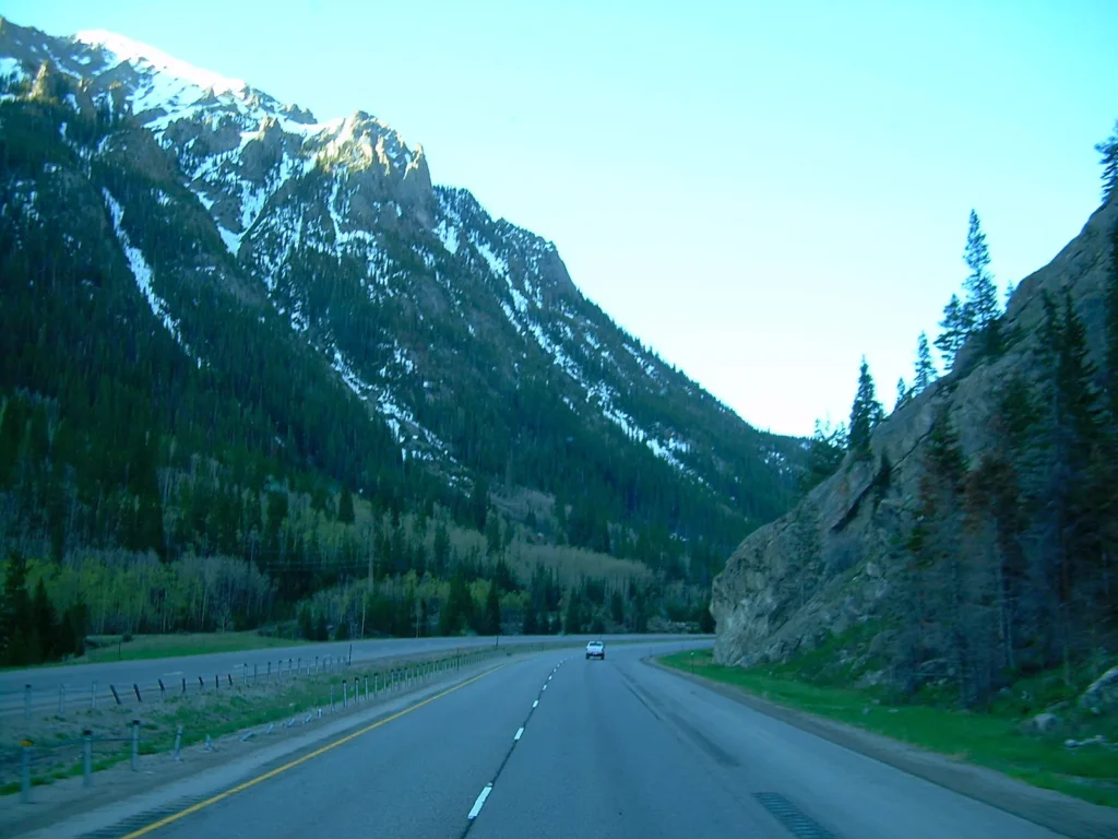 Interstate 70 entre montañas con nieve en las cumbres, ruta típica para manejar con permiso temporal para circular en Colorado