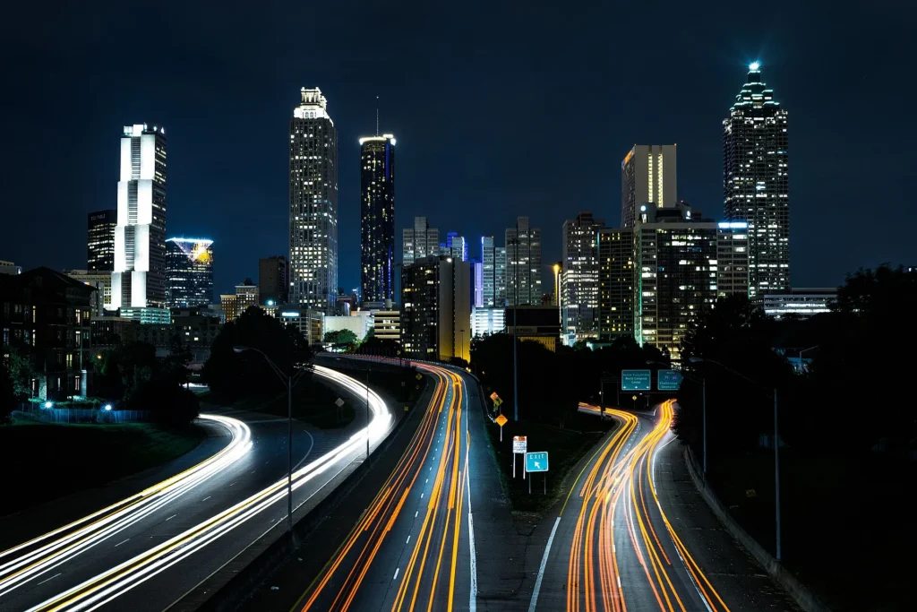 Autopista con estelas de luz que llega al skyline nocturno de Atlanta desde el Jackson Street Bridge, corredor donde se usa la placa temporal en Georgia
