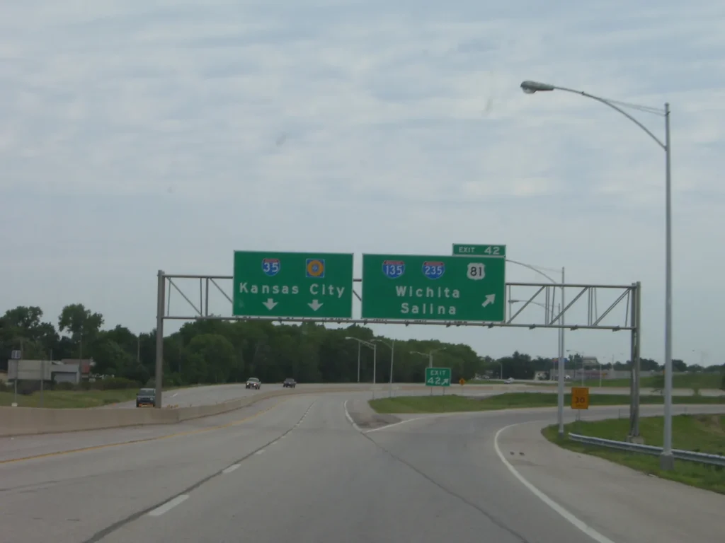 Señales verdes del Kansas Turnpike con destinos a Kansas City, Wichita y Salina sobre la I-35, corredor para circular con placa temporal en Kansas