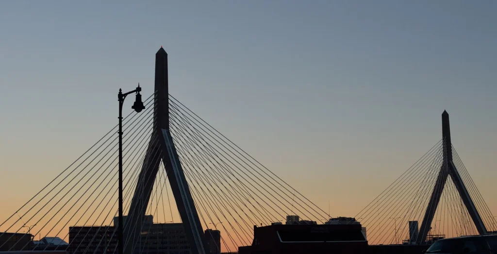 Silueta del puente Zakim Bunker Hill sobre la I-93 al atardecer en Boston, vía por la que circulan los clientes con placa temporal en Massachusetts