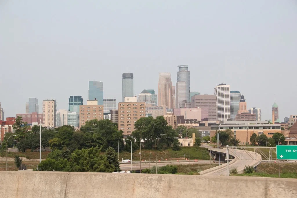 Skyline de Minneapolis visto desde la interestatal con un paso elevado en primer plano, ruta diaria de quien maneja con permiso temporal para circular en Minnesota