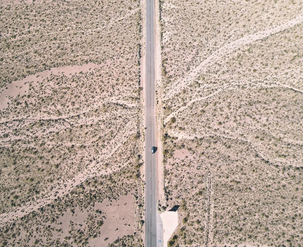 Vista aérea de una carretera recta en el desierto de Nevada con un carro solitario, distancia típica para recorrer con permiso temporal para circular en Nevada