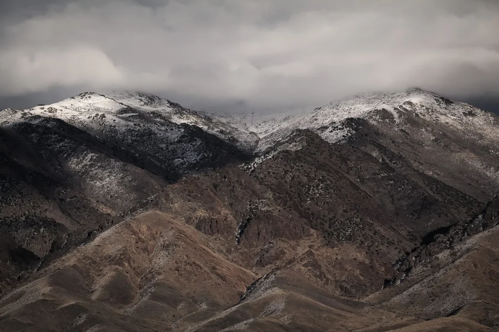 Montañas nevadas y laderas secas bajo cielo nublado en Nevada, paisaje de invierno que se cruza con placa temporal en Nevada
