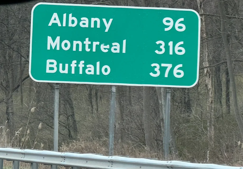 Letrero verde del Thruway hacia Albany, Montreal y Buffalo, ruta común con placa temporal en Nueva York