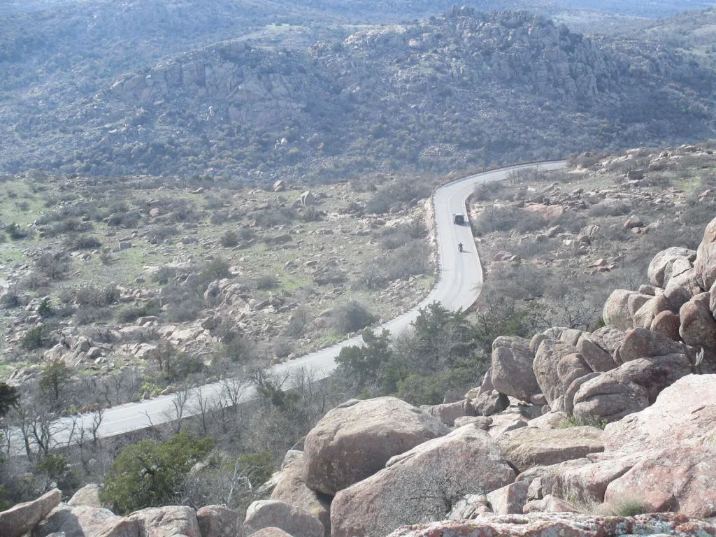 Carretera que serpentea entre rocas de granito vista desde la cima del Mount Scott en las Wichita Mountains, cerca de Lawton, con placa temporal en Oklahoma