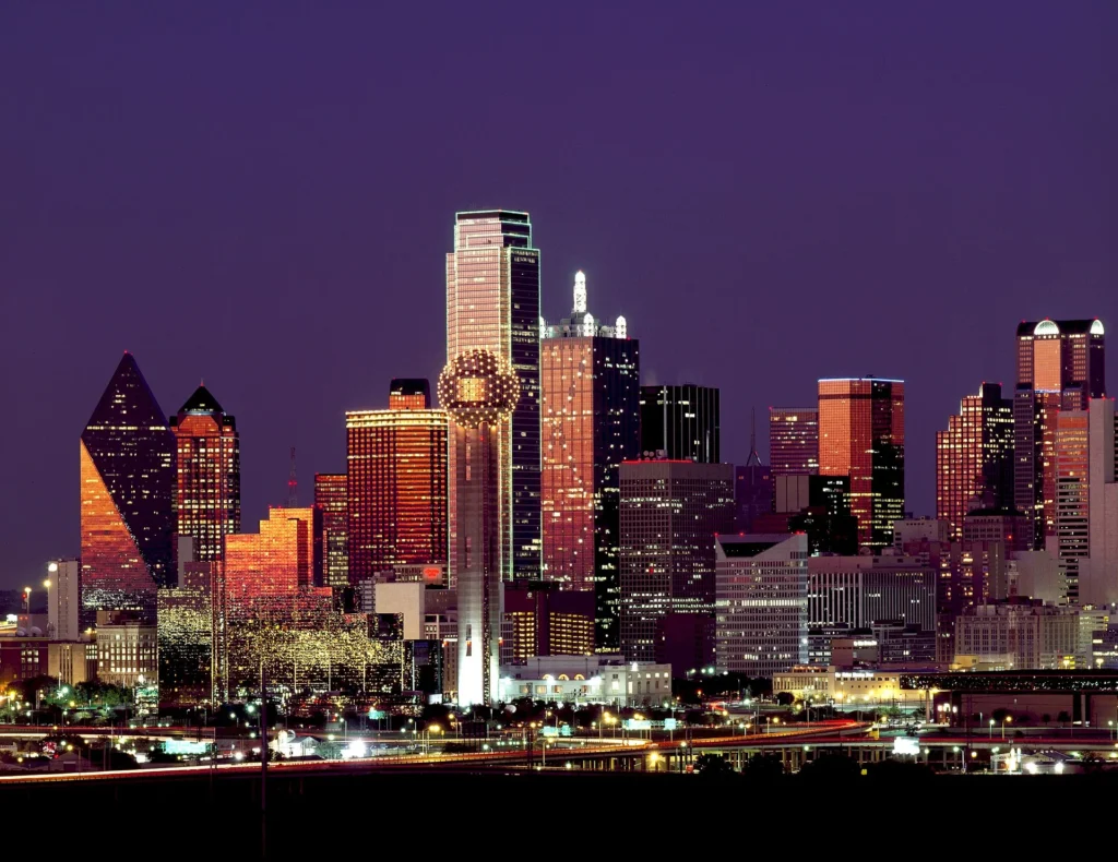 Skyline de Dallas iluminado de noche con la Reunion Tower, área metropolitana donde gestionamos placa temporal en Texas