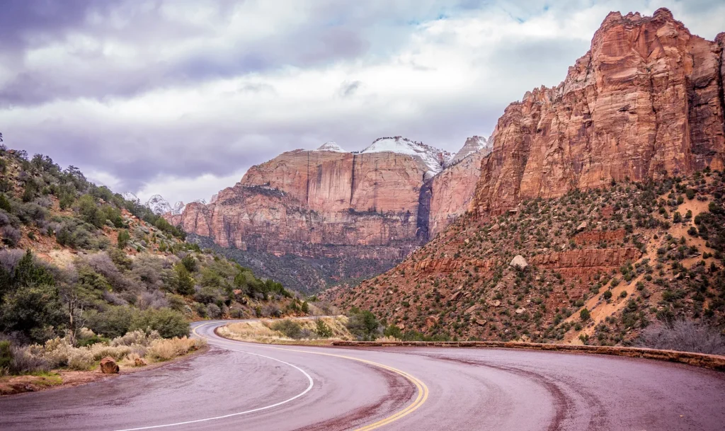Carretera de curvas entre acantilados rojos en el parque Zion, al sur del estado, ruta para manejar con placa temporal en Utah