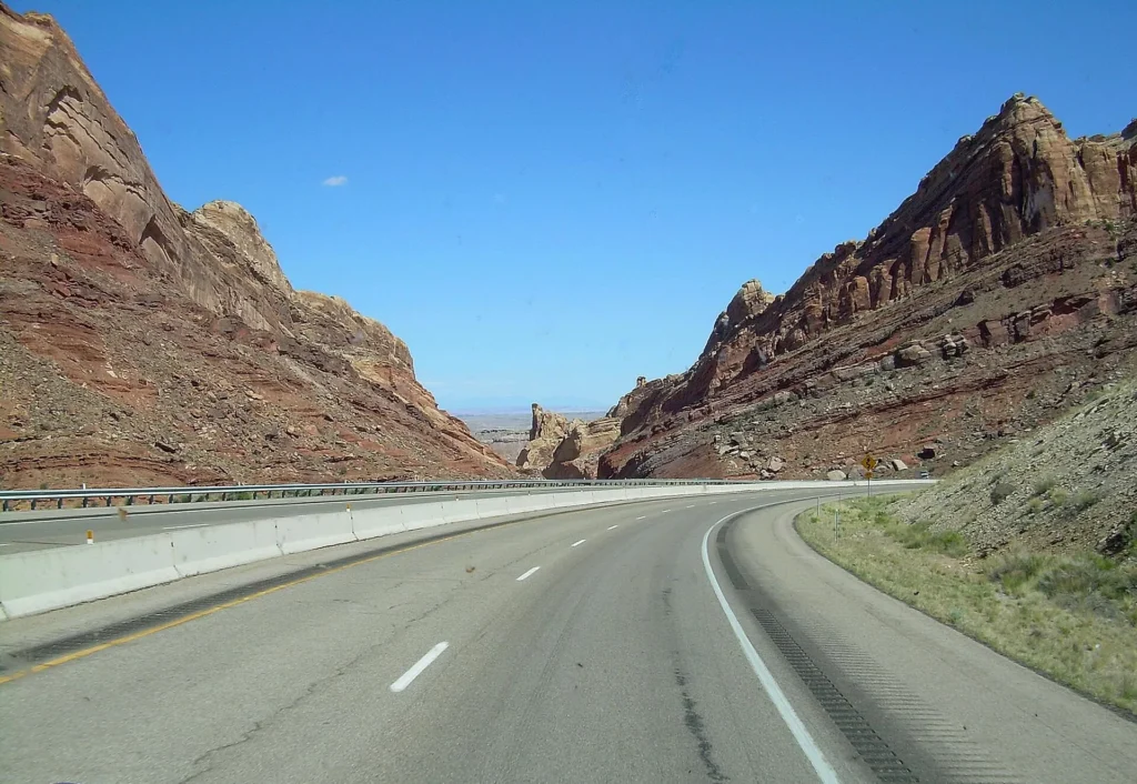 Interstate 70 serpenteando entre paredes de roca roja en el centro de Utah, carretera para manejar con permiso temporal para circular en Utah